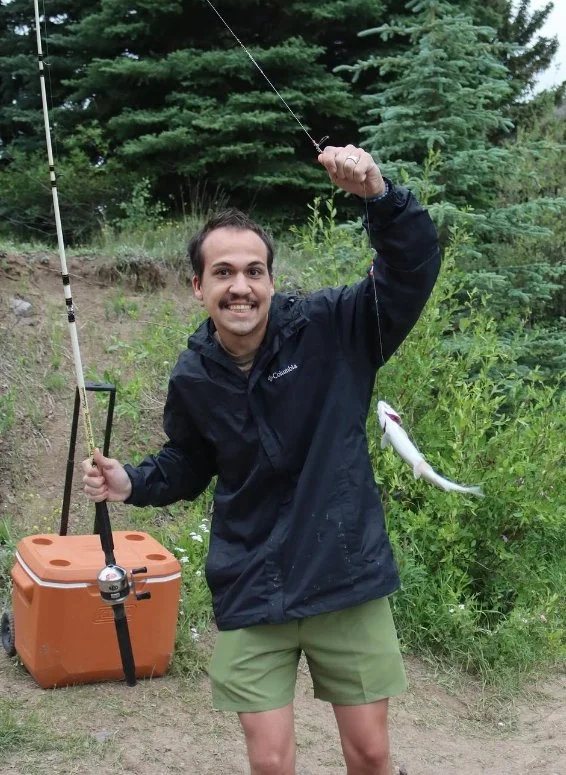 Logan outdoors with a fishing rod and a fresh catch.